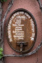 Old wine barrel on a house wall with artistic lettering and painting as a decorative advertising medium for wine sales