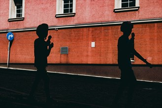 Silhouettes of kids eating ice creams on the street