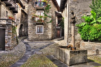Rustic village with a water well made in stone in Arcegno