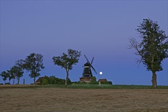 Traditional windmill in field at full moon