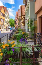 Street scene in Ammergasse with passers-by and shops as well as colourful flower decorations