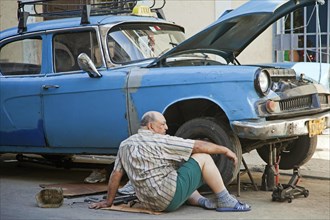 Cuban car mechanic repairing 1950s vintage American cars