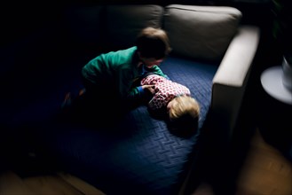 Symbolic photo on the subject of quarrels between siblings. A two-year-old girl and a five-year-old boy fight on a couch at home. Berlin