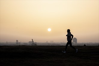 A jogger stands out against the rising sun in Berlin