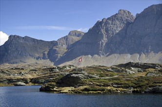 Panoramic view over mountain and an alpine lake with a Swiss flag
