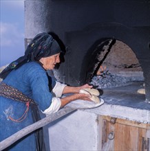 Woman baking bread in the traditional communal oven