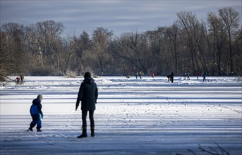 People walk across the ice and skate on the frozen Hermsdorfer See lake in Berlin Reinickendorf. Berlin