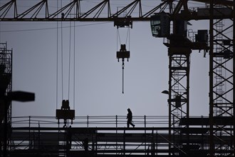 The silhouette of a scaffolder stands out on a construction site in Berlin