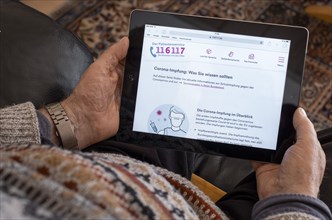 An elderly man holds an iPad with the open website of the patient service www.116117.de