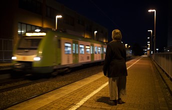 Subject: Elderly woman waiting for a train at night