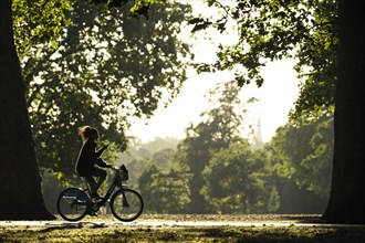 A young girl cycles whilst texting in Hyde Park
