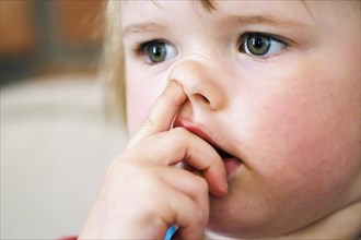 Symbolic photo on the subject of boogers. A little girl picks her nose with her finger. Berlin