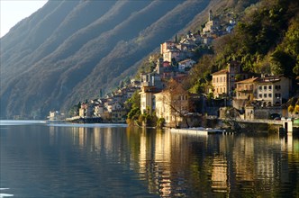 Alpine village reflected in the lake Como with mountain in Lombardy