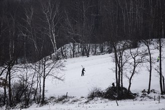 A boy carries skis up a slope in Koenigshain