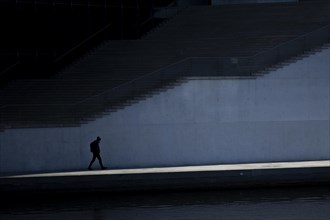 A man in the shade stands out in the sunshine at the Spreebogen in the government district in Berlin