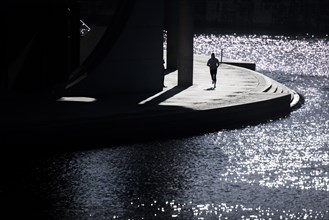 A jogger stands out in the sunshine at the Spreebogen in the government district in Berlin