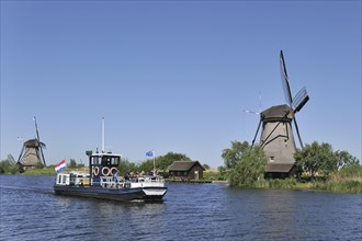 Tourists on sightseeing boat and thatched polder windmills at Kinderdijk