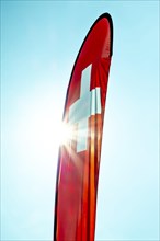 Swiss Banner Flag with Sunbeam and Against Blue Sky
