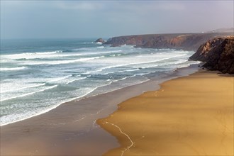 Waves breaking coastal cliffs and sandy beach
