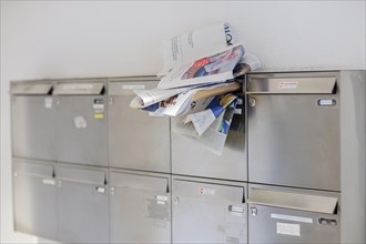 Newspapers and letters stuck in the opening of a crowded letterbox. Berlin