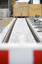 Symbolic photo on the subject of railway infrastructure. A newly built track at Lichtenrade station is covered by a wooden wall. Berlin