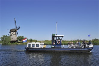 Tourists on sightseeing boat and thatched polder windmill at Kinderdijk