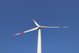 Worm's eye view on blades of wind turbine against blue sky