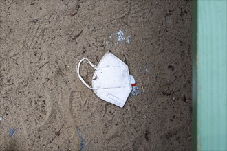 A discarded mouth-nose protection lies on the ground