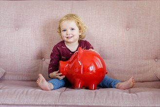 Child with piggy bank is happy.
