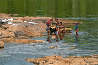 Afro-Surinamese family washing clothes and dishes in the Suriname River near Aurora