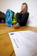 Symbolic photo on the subject of report cards in primary school. A boy poses with a report card. Berlin