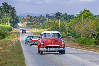 Classic American cars driving along the Carretera Central