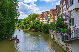 Tourists and excursionists in crowded punting barges are moved up and down the Neckar in front of the Neckar front under the eyes of numerous spectators on the remains of the city wall