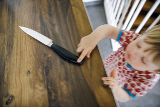 Symbol photo on the subject of dangers in the home. A small child reaches for a knife in the kitchen at home. Berlin