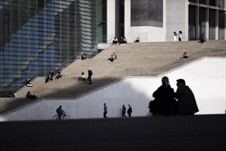 People relaxing in the midday sun at the Spreebogen in the government district in Berlin
