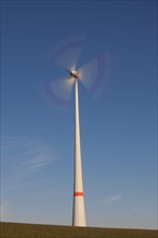 Spinning blades of windturbine against blue sky
