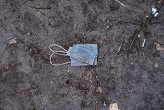A discarded mouth-nose protection lies on the ground