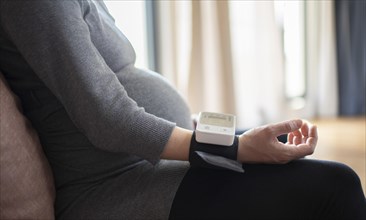 Subject: Pregnant woman measuring her blood pressure