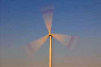 Spinning blades of wind turbine against blue sky
