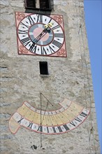Clock and sundial on church tower at Chiusa