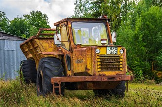 Old and rusted Kockum dump truck parked in front of a tin shed in rural and rustic surroundings