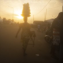 African woman in Togo carries her goods on her head to the market