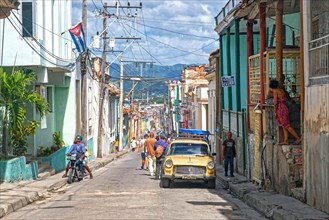 Street scene showing colorful houses and old American car in Santiago de Cuba