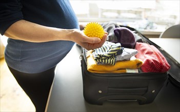 Subject: Pregnant woman packs a suitcase for the clinic.