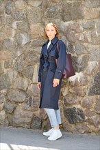 Full length portrait of redhead woman wearing trench coat