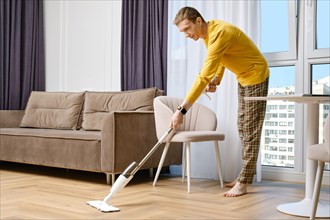 Middle age caucasian man cleaning floor at home with modern swab