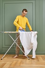 Middle aged man in domestic clothes ironing his shirt