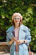 Outdoor portrait of cheerful fashionable woman with lavender in hands