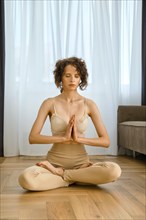Meditative woman sits in lotus position at home