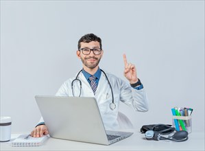 Smiling doctor with laptop with finger up in idea gesture